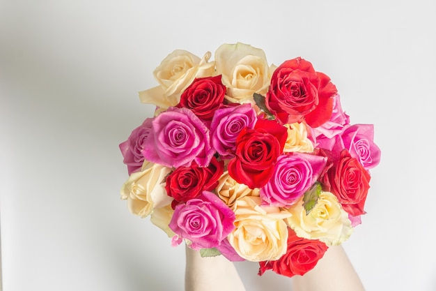 Foto le mani della donna tengono in mano un bellissimo mazzo di rose fresche multicolori