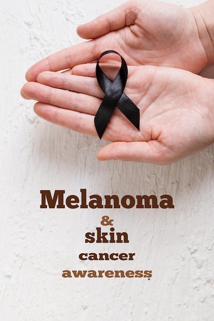 The woman 's hands are holding black Ribbon for symbol Melanoma and skin cancer