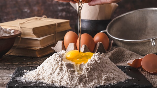 Woman's hands break egg into flour. Toned photo