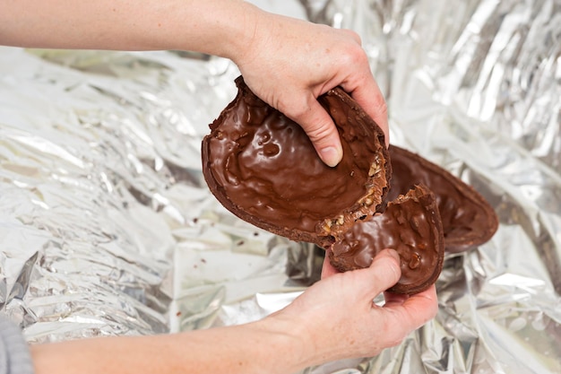 Mani di donna che rompono un uovo di pasqua sfondo confezione d'argento primo piano