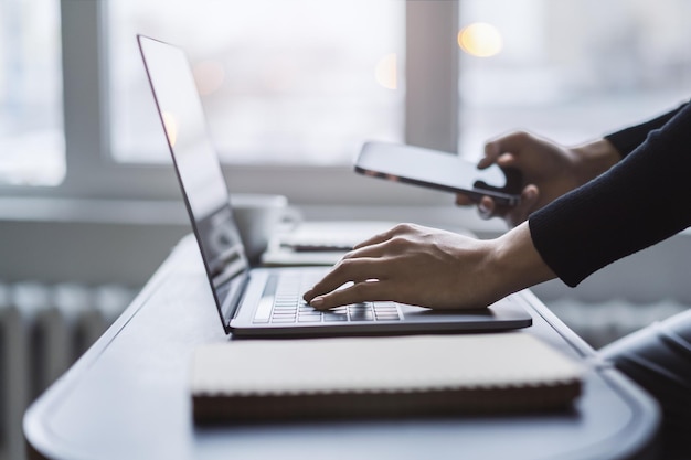 Foto le mani della donna catturate in primo piano mentre digitano su un moderno laptop in mezzo a uno sfondo nebbioso dell'ufficio