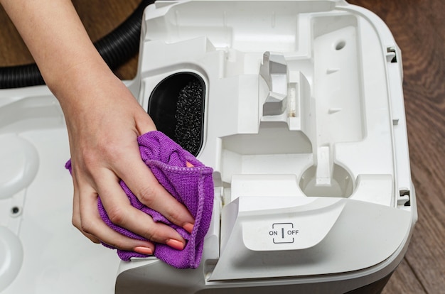 Woman's hands clean and wash the vacuum cleaner from dust and dirt, prevention.