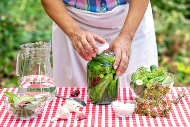 Woman's hands close the can with cucumbers for preservation