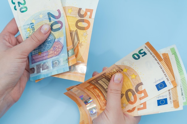 woman's hands counting stack of euro banknotes on blue background money business finance