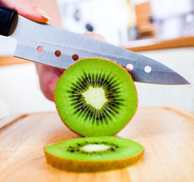 woman's hands cutting fresh kiwi on kitchen
