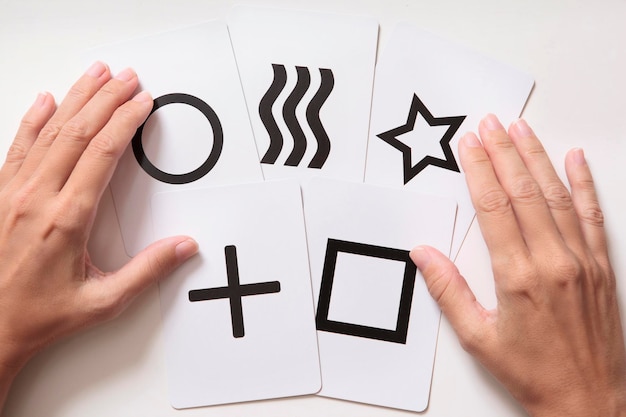 Photo woman's hands doing mentalism trick with zener cards top view white background