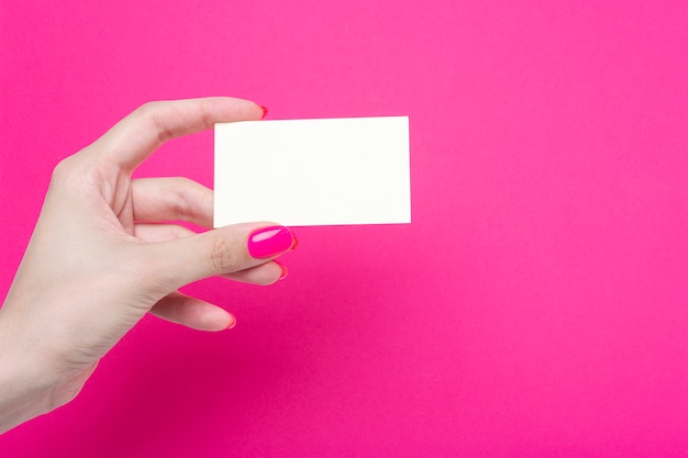 Woman's hands hold blank business card isolated on pink paper