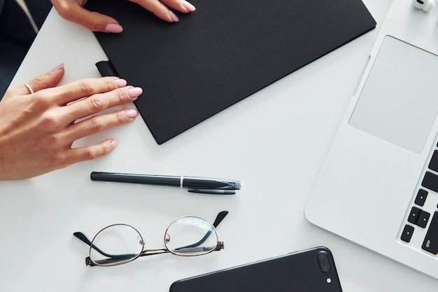 Woman's hands holding black colored notepad that lying on the table