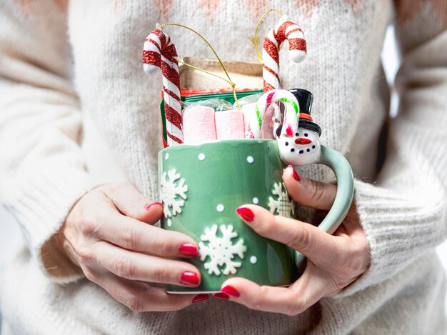 クリスマスのお菓子とクリスマス カップを保持している女性の手