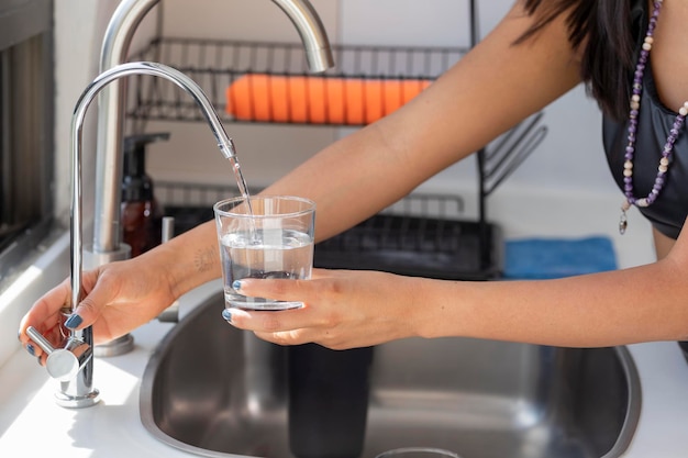 水道水で満たされたガラスを保持している女性の手