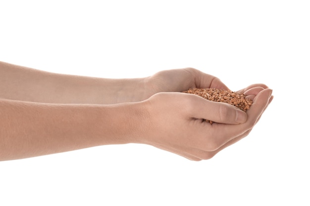 Woman's hands holding raw buckwheat on white background