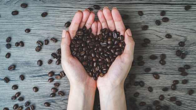 woman's hands holding roasted coffee beans with heart shaped