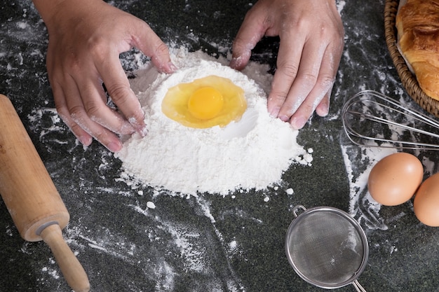 Woman's hands knead dough with flour, eggs and ingredients