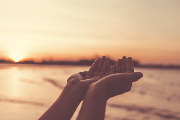 Woman's hands placed together on a beautiful beach