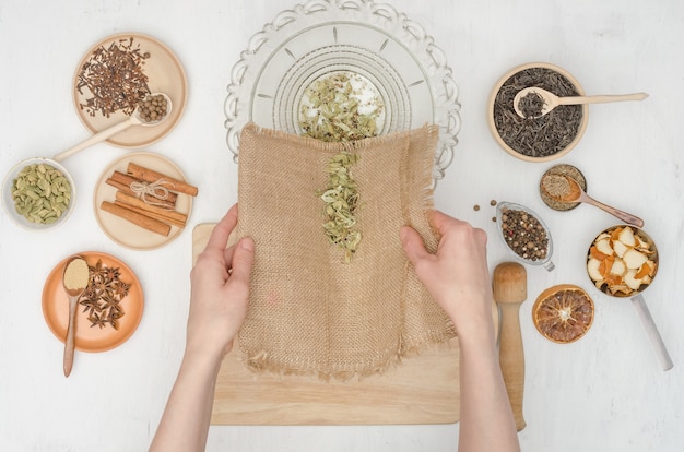 Mani della donna che preparano il tè indiano di masala con le spezie