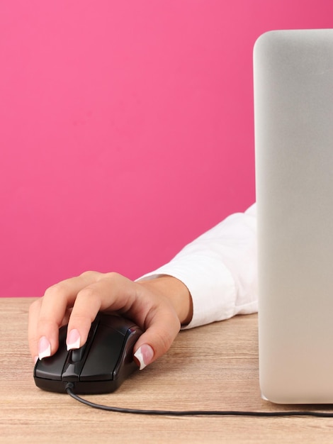 Фото Женские руки нажимают клавиши компьютерной мыши на розовом фоне крупным планом