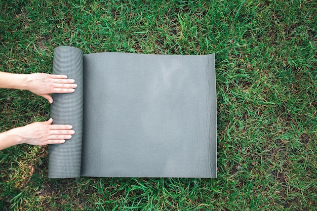 Woman's hands rolling up the mat on grass