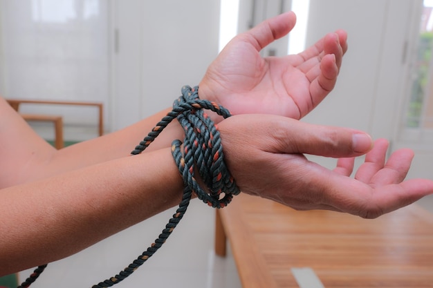 A woman's hands tied with a dark rope