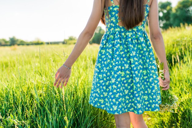 女性の手が草原の草に触れる