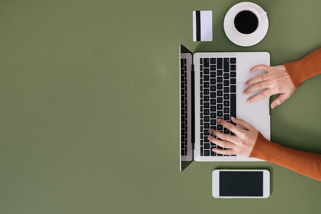 Woman's hands typing on white laptop with black keyboard