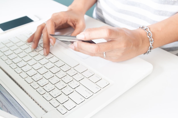 Le mani della donna usando il computer portatile e la carta di credito. pagamento online, internet banking