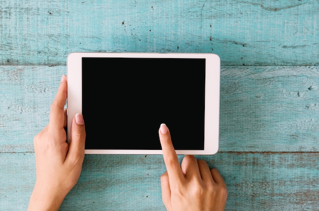 Woman’s hands using tablet with blank screen.