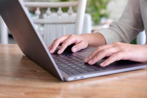 Mani della donna utilizzando e digitando sulla tastiera del computer portatile sul tavolo