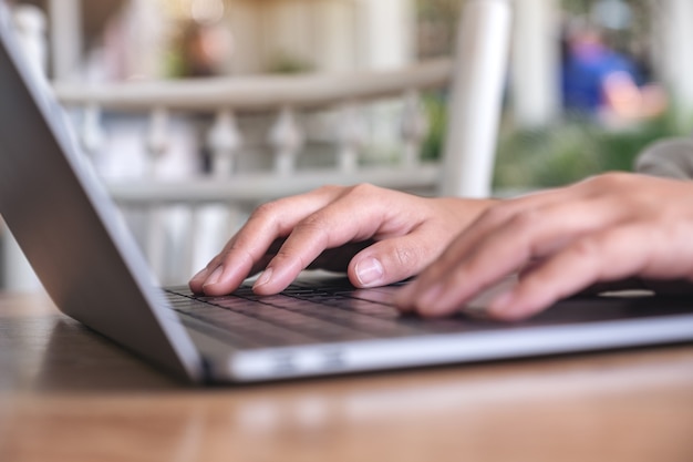 Mani della donna utilizzando e digitando sulla tastiera del computer portatile sul tavolo