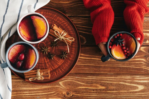 Woman's hands in warm sweater holding a cup of mulled wine