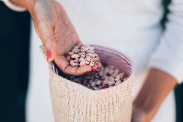 写真 一握りの生の斑点豆と女性の手