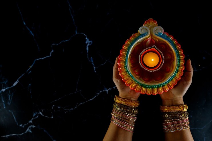Photo woman's hands with henna holding lit candle for diwali festival