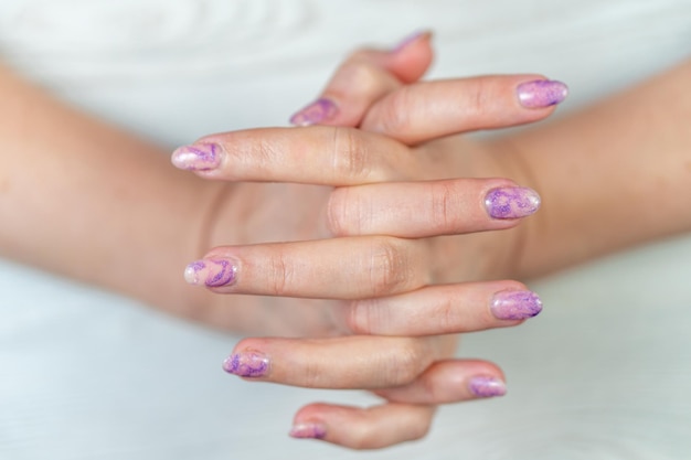 A woman's hands with purple nails and purple nail polish.