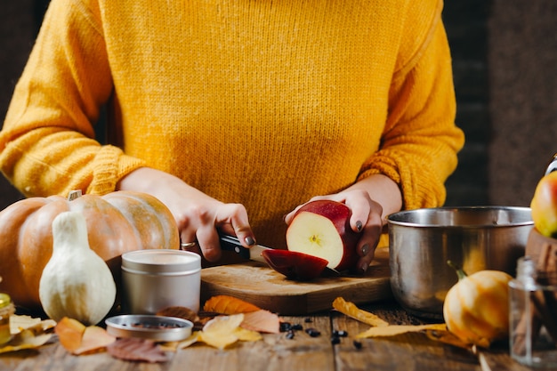 woman's hands in yellow sweater cutting apples for hot wine.