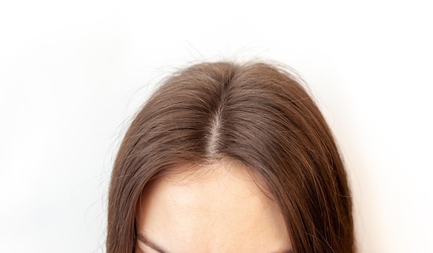 A woman's head with a parting of gray hair that has grown roots due to quarantine