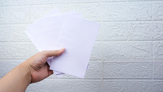 Woman's hold envelope over white wall background