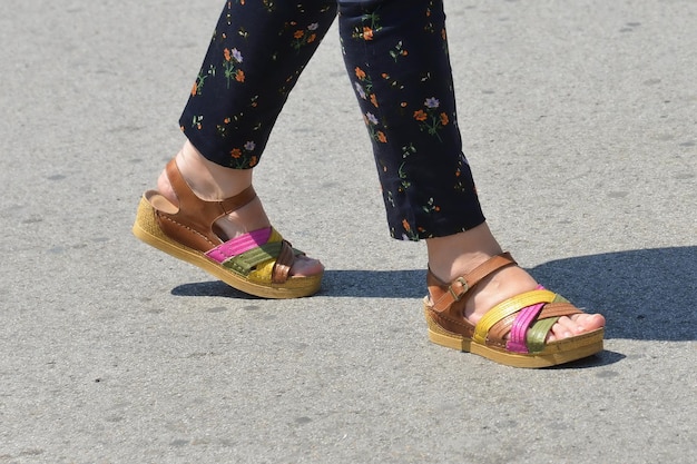 Woman's legs in various colors sandals walking on the street