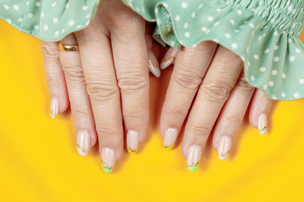 A woman's nails with a green and yellow polka dot pattern.