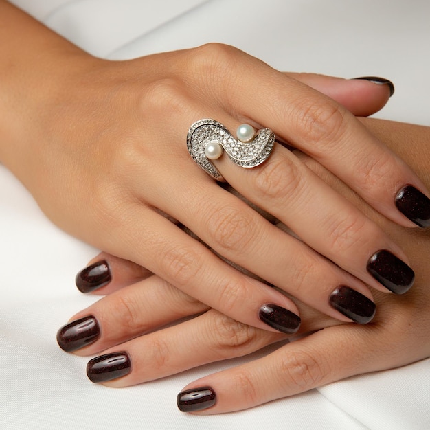 A woman's nails with a ring on the middle finger.