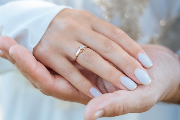 A woman's palm with a gold ring on her finger lies in a man's palm