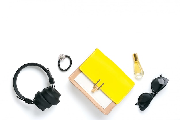 Woman's set accessories Yellow, beige handbag, wireless headphones, perfume, scrunchy, black sunglasses isolated  Top view Flat lay