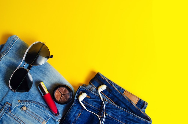 Woman's things, elegant accessories . jeans, lipstick, glasses, headphones. place for text