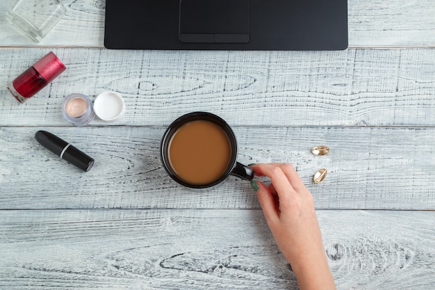 woman's workplace with laptop, coffee Cup and cosmetics