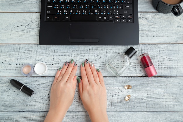 Posto di lavoro della donna con laptop, tazza di caffè e cosmetici