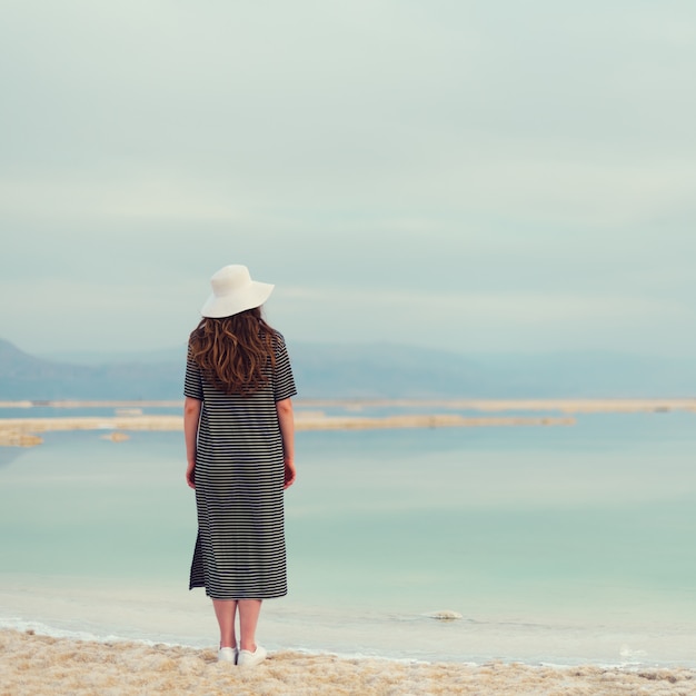 Foto donna in abito da marinaio a strisce vicino al mare della spiaggia del mar morto