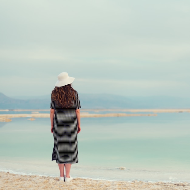 Woman in sailor striped dress near seaside of Dead Sea beach