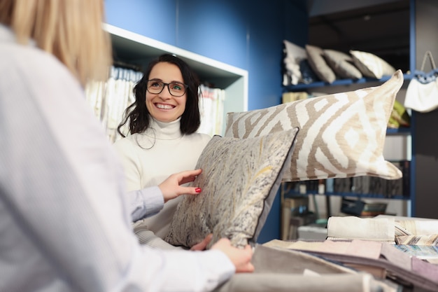 Женщина-продавец показывает декоративную подушку в концепции дизайнерских услуг салона