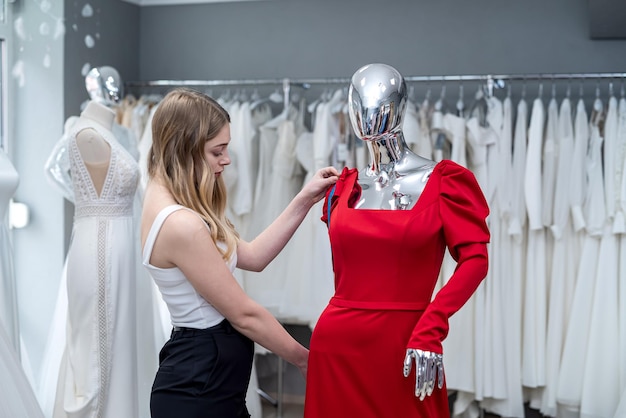 Woman saleswoman measures evening dress with tape measure in the salon