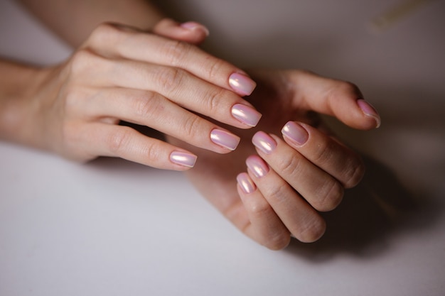 Woman in salon receiving manicure by nail beautician