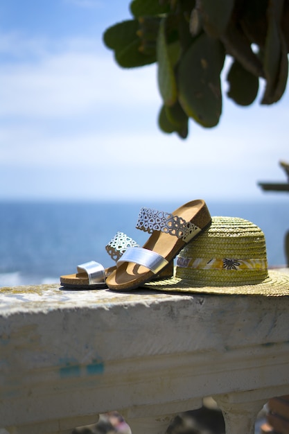 Esposizione sandali donna e cappello di paglia con il mare sullo sfondo