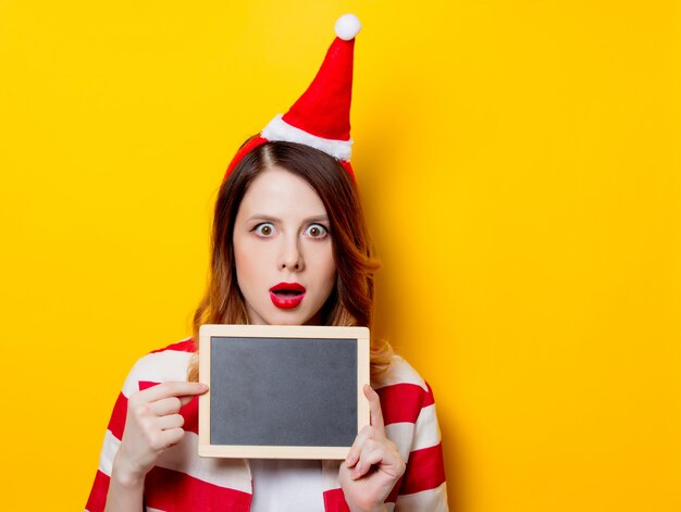 woman in Santa Claus hat with blackboard